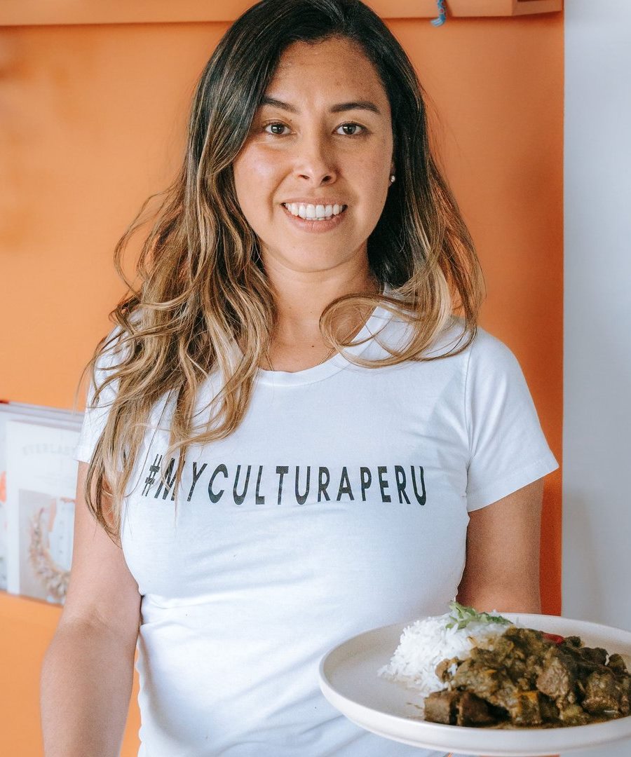 Cinthya, founder and head chef of MyCultura Peru, holding a plate of seco with rice.